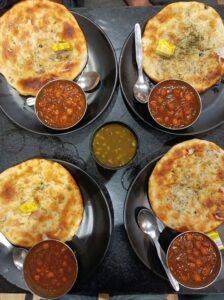 Delicious Delhi chole bhature meal served on black plates at an Indian restaurant.