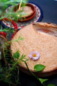 Close-up of traditional Bangladeshi dessert garnished with a flower, showcasing vibrant colors and textures.